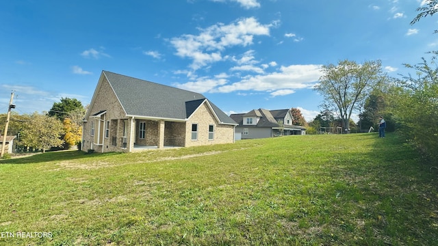 back of property with a yard and brick siding