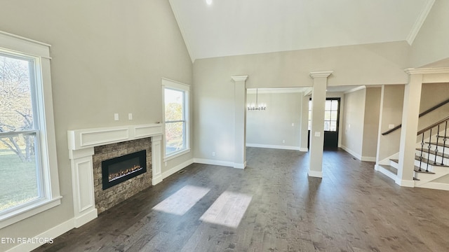 unfurnished living room with decorative columns, dark wood finished floors, a glass covered fireplace, baseboards, and stairs