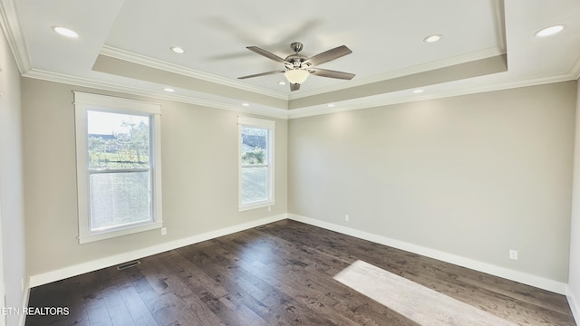 spare room with dark wood-style floors, a tray ceiling, and baseboards