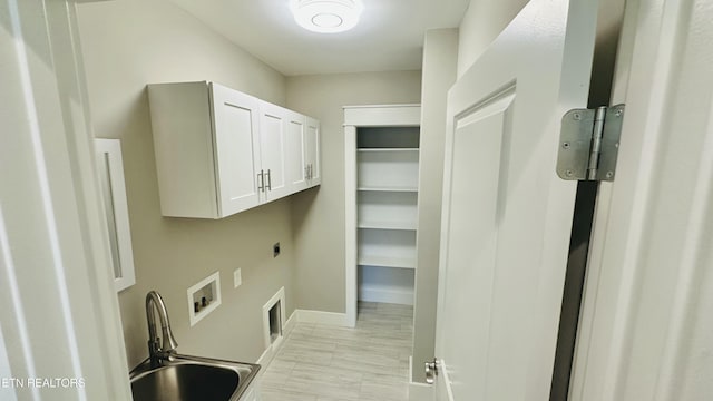 clothes washing area featuring washer hookup, cabinet space, a sink, electric dryer hookup, and baseboards