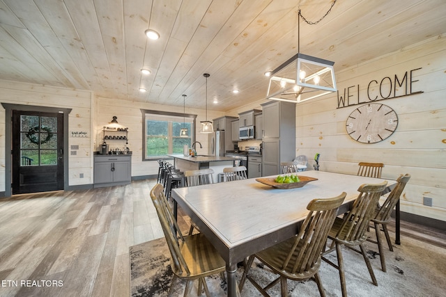 dining space featuring a chandelier, hardwood / wood-style floors, wooden ceiling, and wooden walls