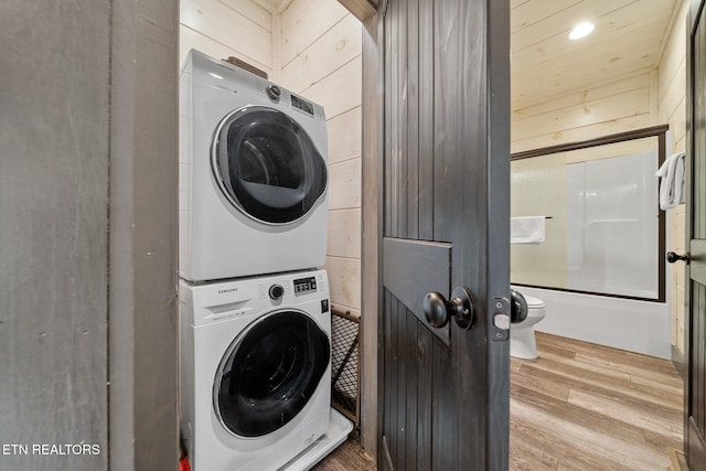 washroom featuring wood-type flooring and stacked washer / drying machine