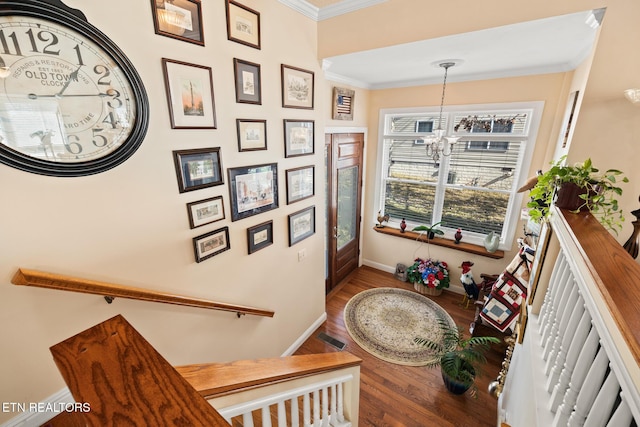 stairway featuring hardwood / wood-style floors, crown molding, and an inviting chandelier