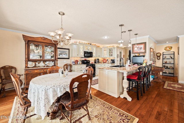 dining area featuring hardwood / wood-style flooring, a notable chandelier, crown molding, and sink