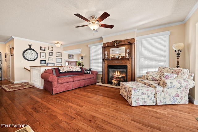 living room featuring ceiling fan, hardwood / wood-style floors, a textured ceiling, and ornamental molding