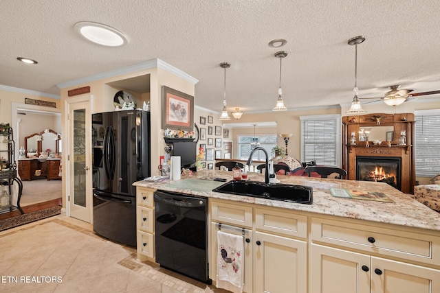 kitchen featuring crown molding, sink, black appliances, cream cabinetry, and hanging light fixtures