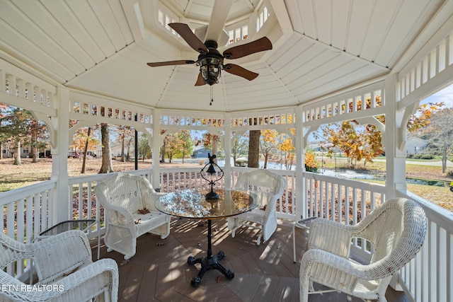 sunroom featuring ceiling fan, a water view, and vaulted ceiling