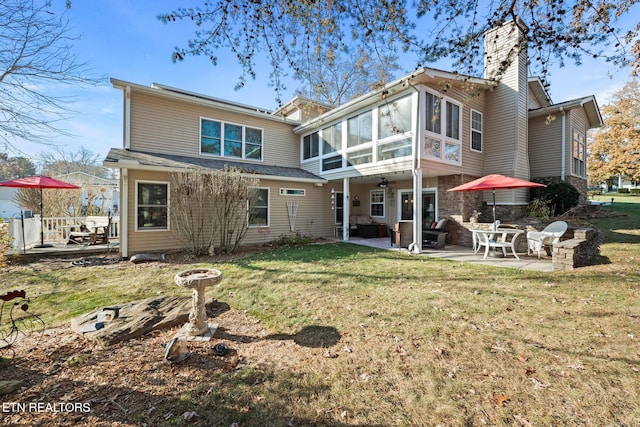 back of property featuring a lawn, a patio area, and a sunroom