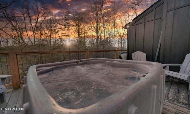 deck at dusk featuring a hot tub