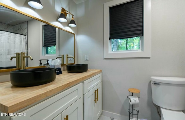 full bath with a shower with curtain, baseboards, vanity, and toilet