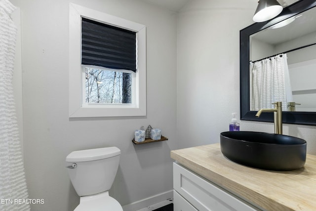 bathroom featuring toilet, vanity, and baseboards