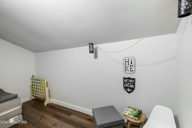 sitting room with lofted ceiling, baseboards, dark wood finished floors, and a textured ceiling