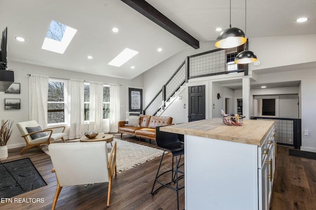 kitchen featuring white cabinetry, open floor plan, dark wood-style floors, lofted ceiling with skylight, and decorative light fixtures