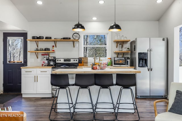 kitchen featuring stainless steel appliances, white cabinetry, hanging light fixtures, and open shelves