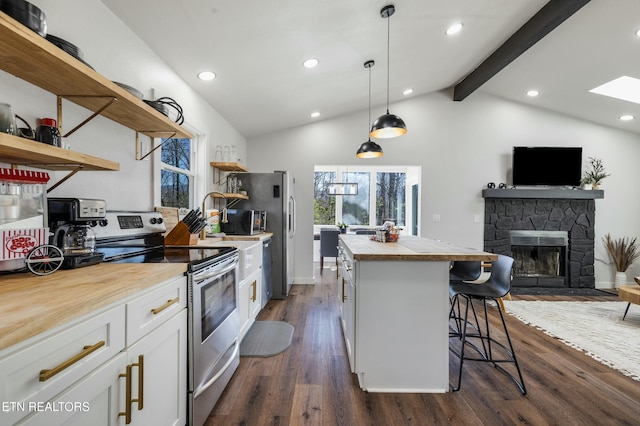 kitchen featuring a breakfast bar area, hanging light fixtures, stainless steel range with electric stovetop, white cabinetry, and open shelves