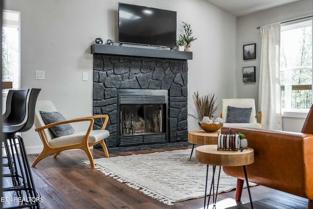 sitting room with a fireplace, wood finished floors, and baseboards