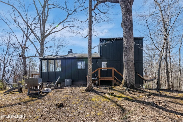 exterior space with central AC, a chimney, and board and batten siding