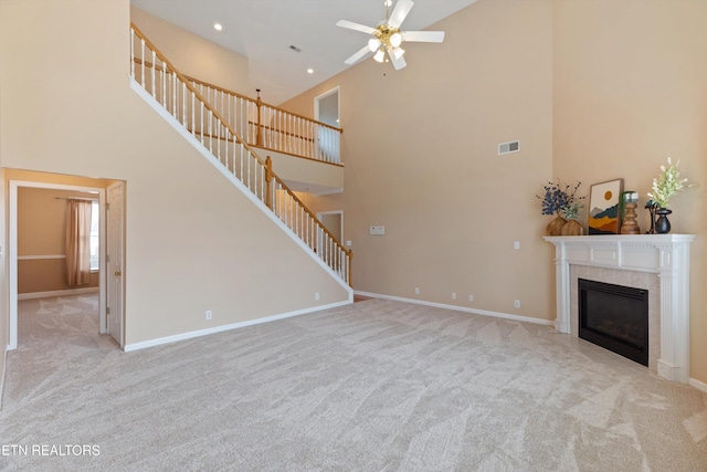 unfurnished living room featuring light colored carpet, a tile fireplace, and ceiling fan