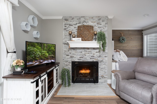 living room featuring a stone fireplace, crown molding, and hardwood / wood-style floors