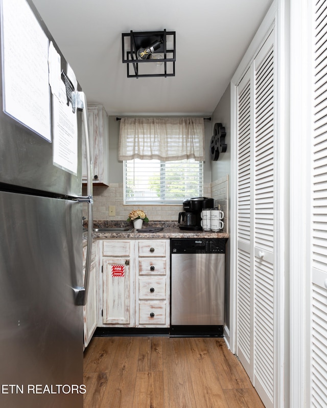 kitchen with decorative backsplash, hardwood / wood-style floors, stainless steel appliances, and white cabinetry