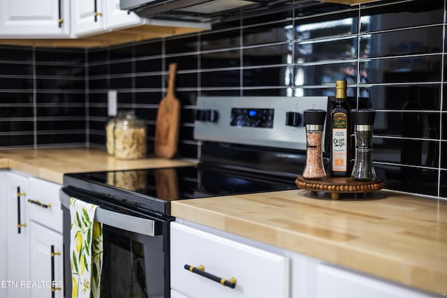 kitchen with stainless steel electric stove, decorative backsplash, and white cabinetry