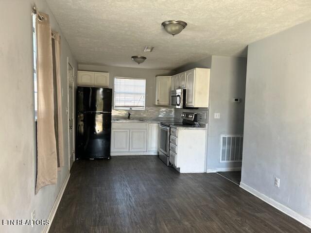 kitchen with sink, tasteful backsplash, dark hardwood / wood-style floors, a textured ceiling, and appliances with stainless steel finishes