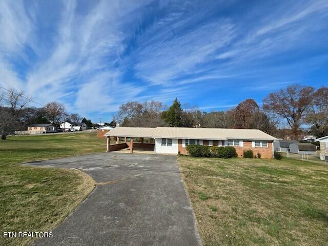 single story home featuring aphalt driveway, a carport, and a front lawn