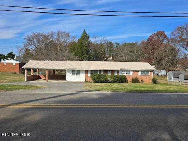 ranch-style house with an attached carport, driveway, and a front lawn