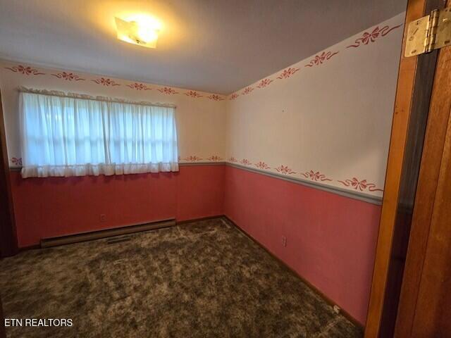 carpeted spare room featuring a baseboard heating unit