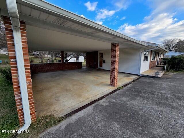 view of parking with driveway and an attached carport