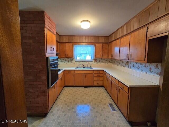 kitchen featuring wall oven, brown cabinets, and light countertops