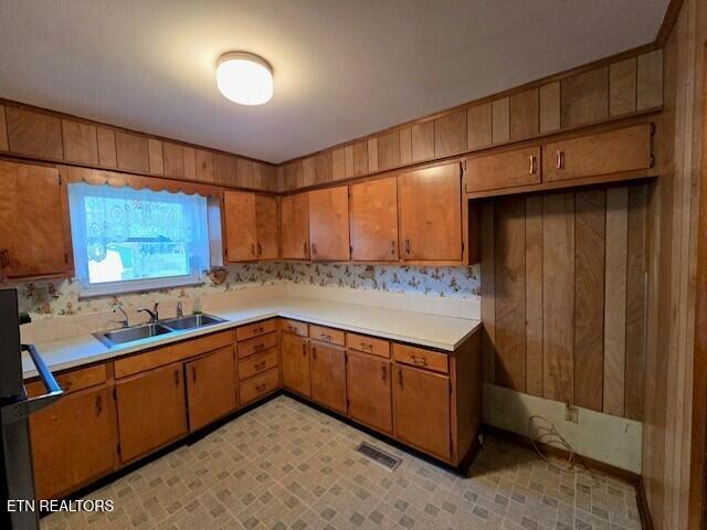 kitchen with brown cabinetry, light countertops, a sink, and visible vents