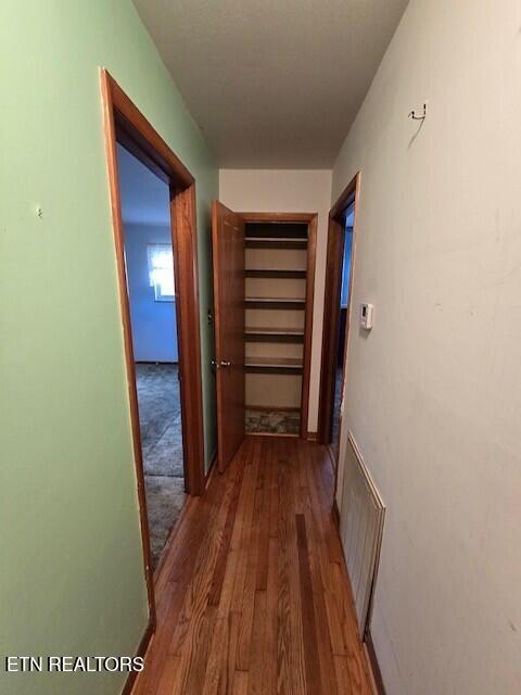 hallway featuring wood finished floors, visible vents, and baseboards