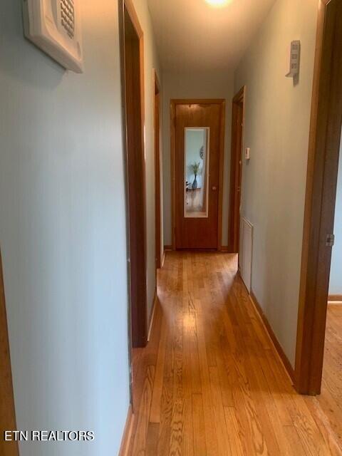 corridor featuring light wood finished floors and baseboards