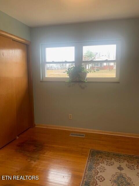 spare room with wood finished floors, visible vents, and baseboards