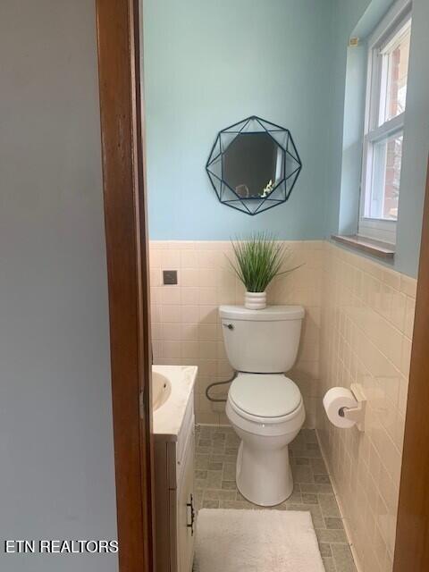 bathroom featuring a wainscoted wall, tile walls, and vanity