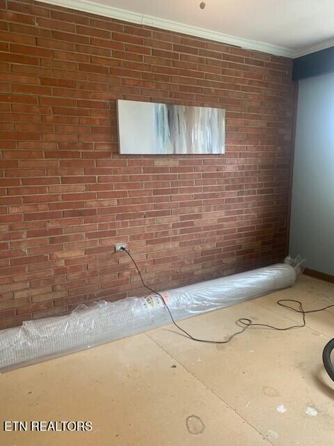 interior space with brick wall and crown molding