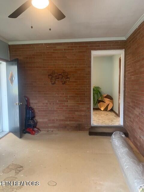 spare room with brick wall, ornamental molding, and a ceiling fan