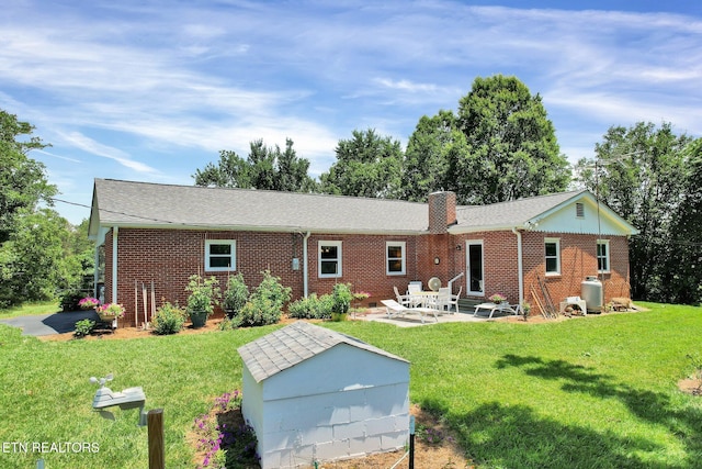 back of property featuring a lawn, a patio area, and an outbuilding