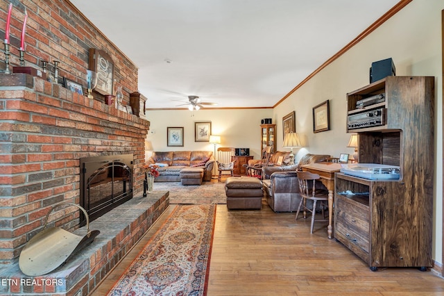 living room featuring light hardwood / wood-style floors, a brick fireplace, ceiling fan, and crown molding