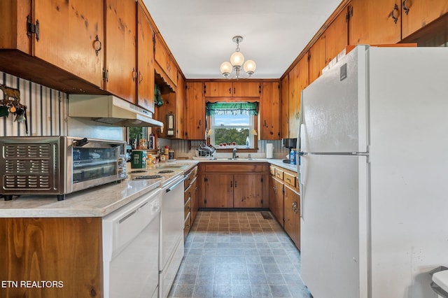 kitchen featuring backsplash, sink, a chandelier, and white appliances