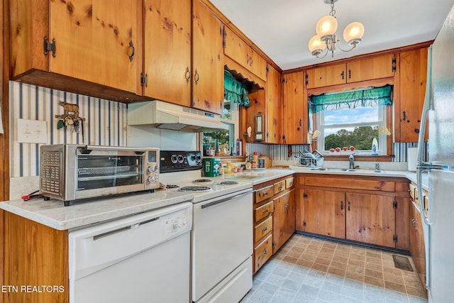 kitchen featuring pendant lighting, white appliances, sink, decorative backsplash, and a chandelier