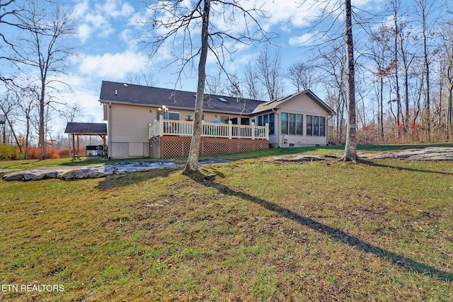 rear view of property featuring a lawn, a wooden deck, and a sunroom