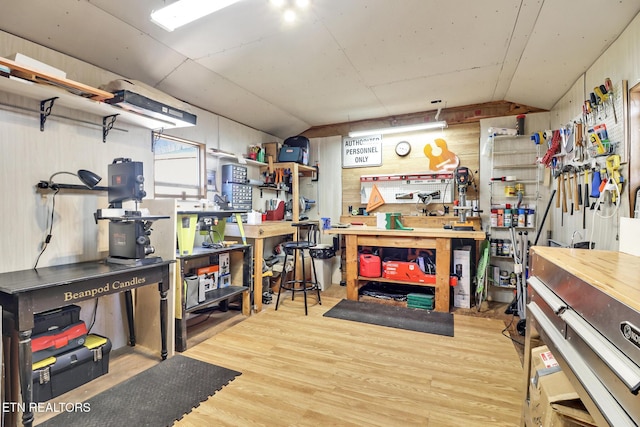 basement with a workshop area, light hardwood / wood-style floors, and wood walls