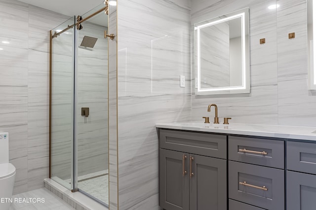 bathroom featuring vanity, toilet, a shower with shower door, and tile walls