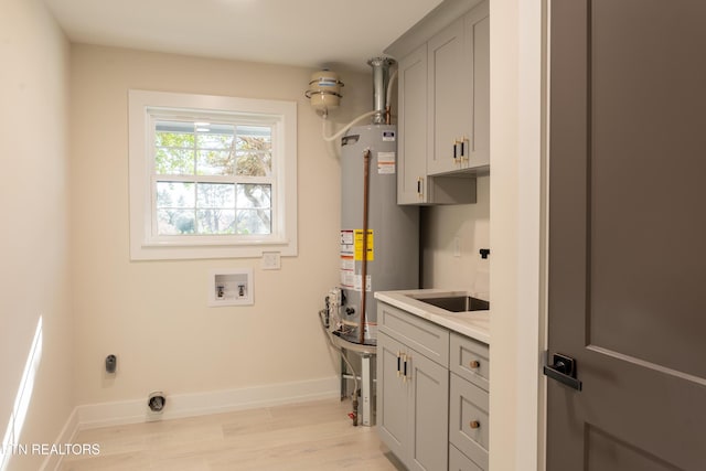 laundry area featuring cabinets, hookup for a washing machine, electric dryer hookup, water heater, and light hardwood / wood-style flooring