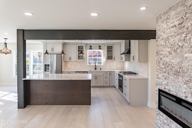 kitchen with sink, a kitchen island, appliances with stainless steel finishes, decorative light fixtures, and beam ceiling