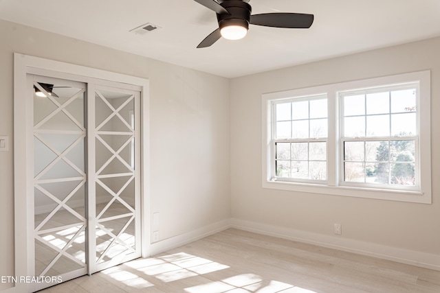 empty room featuring ceiling fan, a wealth of natural light, and light hardwood / wood-style flooring