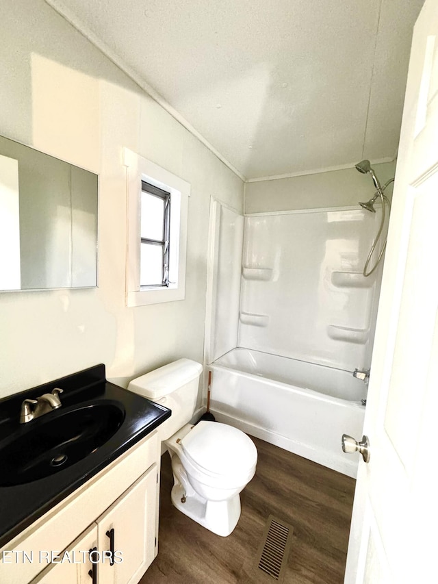 full bathroom with hardwood / wood-style floors, vanity, bathtub / shower combination, toilet, and a textured ceiling