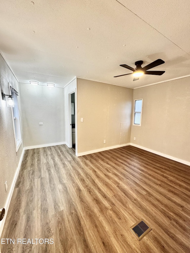 empty room with ceiling fan, wood-type flooring, and a textured ceiling